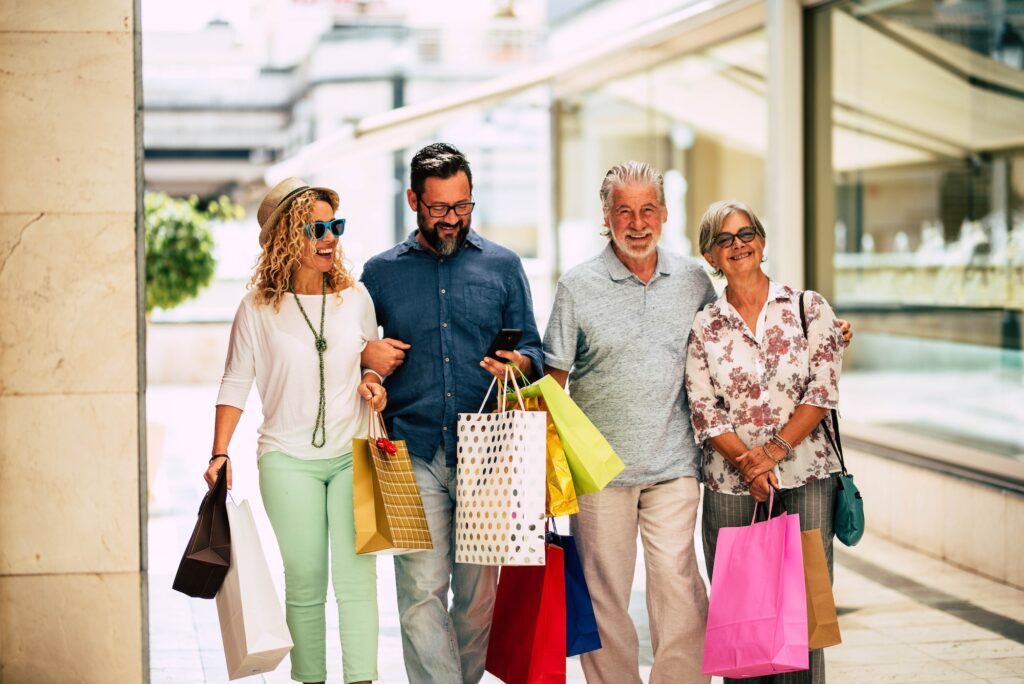 group of four people and family go shopping together holding a lot of shopping bags